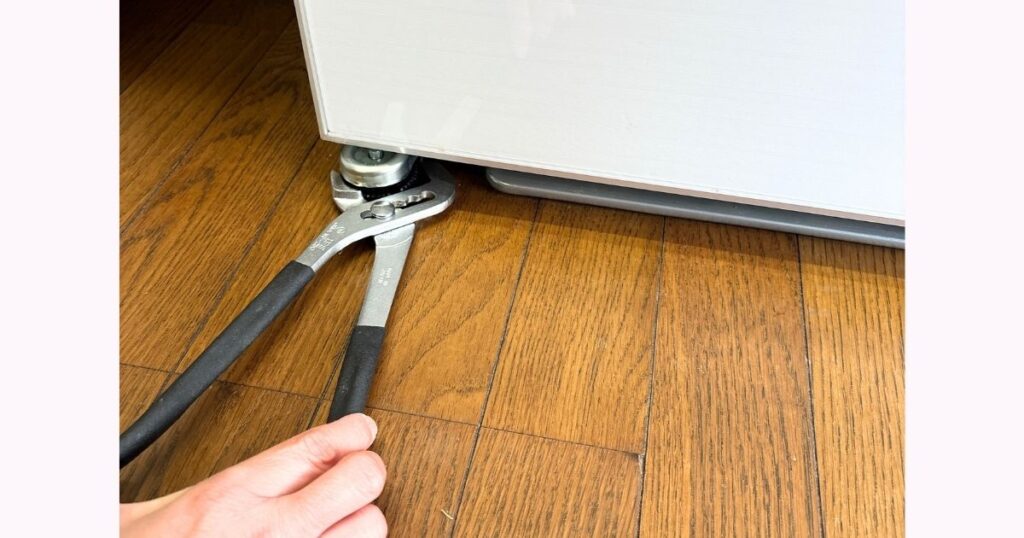 挟む幅を変えられるウォーターポンププライヤーを使用して、調整脚を実際に回す様子。