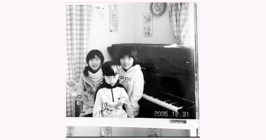 ピアノの前で3人の子どもたちが微笑んでいる2005年12月31日に撮った写真