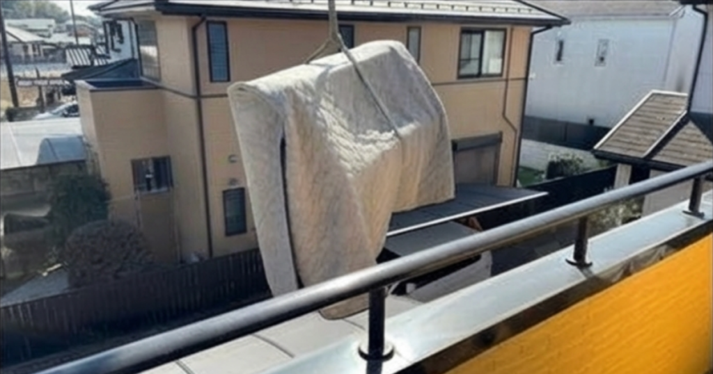 ロープで縛っったピアノが2階からクレーンで降ろされる様子