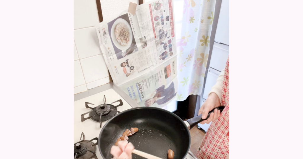 油はね対策に新聞紙を壁に立てかけてコンロで調理している様子