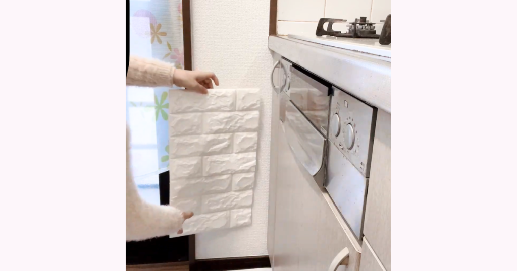 キッチンの壁にタイルシートを当てて位置を確認している様子
